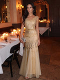 Karena Floor Length Dress Gold - Order In worn by a model in a stylish dining setting, featuring intricate sequins and cap sleeves.
